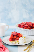 Strawberry jelly pie with a scoop of vanilla ice-cream and pistachios on tile background