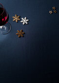 Red wine glass, stars and snowflake decoration on a dark blue tablecloth