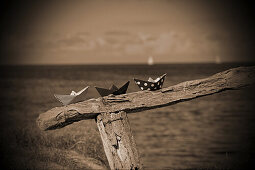 Paper boats on a wooden railing