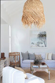 Sitting area in living room with high white ceiling and straw pendant lamp