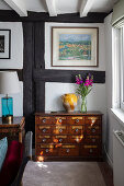Antique mahogany apothecary cabinet, painting above in living room with a timber framed wall