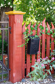 Red painted wooden fence with letterbox