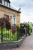 House facade with different colored bricks and front garden with wrought iron fence