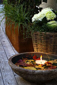 Wasserschale mit Blättern und Schwimmkerze auf der Terrasse