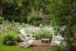 White garden chairs on gravel terrace in garden