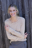 Young blond woman in striped shirt in front of board wall