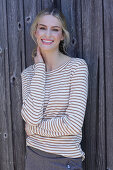 Young blond woman in striped shirt in front of board wall