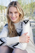 Young blond woman in light-coloured knitted dress with Norwegian pattern
