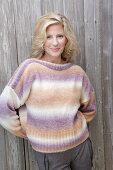 Mature blonde woman in knitted jumper with colour gradient