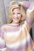 Mature blonde woman in knitted jumper with colour gradient