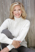 Mature blonde woman in white knitted jumper and grey leggings