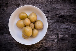 Small baked potatoes in a bowl on a wooden background