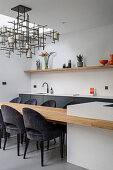 Wooden dining table extended from the kitchen island and elegant upholstered chairs