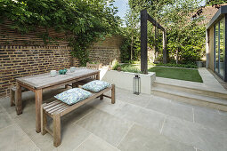 Wooden table with benches in front of brick wall on terrace