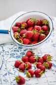 Fresh strawberries for strawberry jam on table and in enamel sieve
