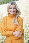 Junge blonde Frau in gelbem Rollkragenpullover in der Natur