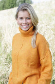 Junge blonde Frau in gelbem Rollkragenpullover in der Natur