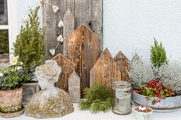 Winter arrangement with plants, sculpture of a woman's bust and, wooden house silhouettes on the terrace