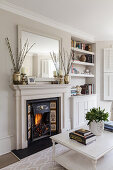 Coffee table in front of fireplace with fire in a bright living room