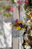 Spring bouquet hanging in a hanging basket at a window