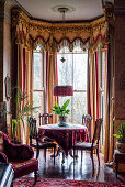 Tisch und Stühle im Erker mit luxuriösen Vorhängen