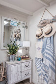 Driftwood fish as wall coat rack with sun hats and towels, wooden cabinet, and mirror in the hallway
