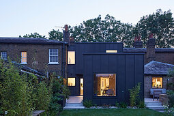 View from garden to new modern building with a zinc exterior at dusk