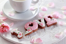 Schriftzug 'LOVE' aus glasierten Lebkuchenplätzchen neben einer Tasse Espresso