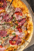 Pizza mit Salami, Schinken und Tomaten (Close up)