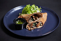 Crepe with mushroom and spinach filling on a blue plate