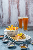 Tasty fried potatoes with breaded chicken wings placed on table with set of sauces in light kitchen