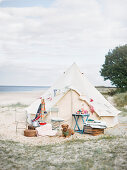 Chairs, table and dog in front of closed tent by the sea