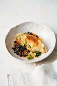 Turnip and pea strudel on black beans in a sesame seed broth