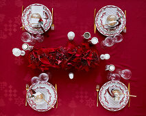 Christmas table setting with red tablecloth and garland of red poinsettia