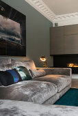 Velvet sofa with throw pillows, in the background fireplace in the living room with stucco ceiling