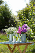 Sträuße aus Holunderblüten, Wicken und Wiesenkerbel auf Gartentisch