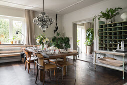 Solid wood table with flea market chairs, pendant lamp with glass spheres above in the dining room