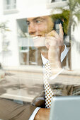 A young businessman on the phone behind a window