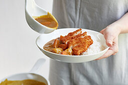 Pouring curry sauce over chicken katsu