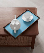 A tray with a tea set on a designer teak chest with a rattan weave