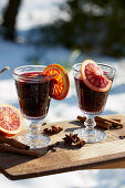 Mulled wine with blood orange on a table in a wintery garden