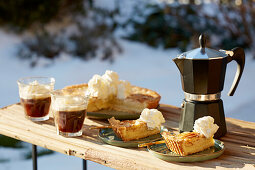Apfelkuchen mit Kaffee auf Tisch im winterlichen Garten