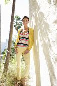 Young brunette woman wearing a striped tankini top, yellow pants and jacket