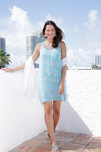 Brunette woman in printed sundress and towel on the beach