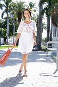 Brunette woman with bag in summer dress with embroidery