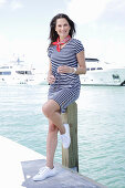 Brunette woman in a striped summer dress by the sea