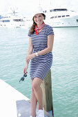 Brunette woman in a hat in a striped summer dress near the sea