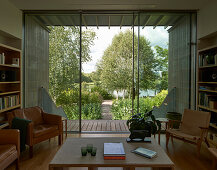 Living room with bookshelves and seating furniture, view of garden