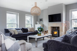 Living room with velvet sofas, marble table, and fireplace