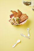 Meeresfrüchtesalat mit Knäckebrot serviert in großer Muschelschale mit Perlmutt-Löffeln